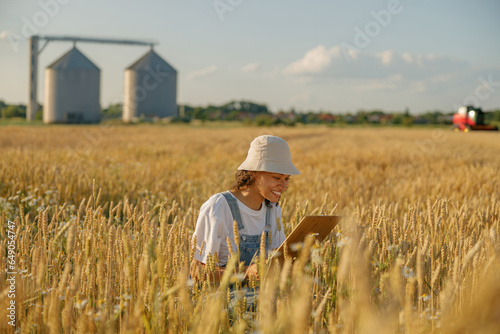 Smiling woman agronomist with tablet in a wheat field checks the harvest. High quality photo