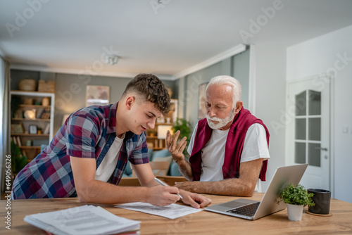 student caucasian male teenager and his grandfather or professor study
