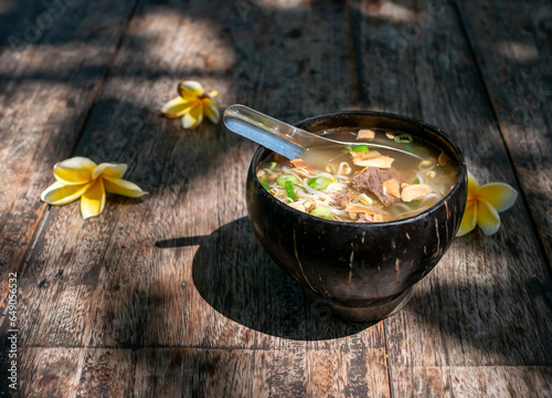 Soto Batok, a traditional Javanese beef soup with vegetables and rice, served in a traditional bowl made of coconut shell photo