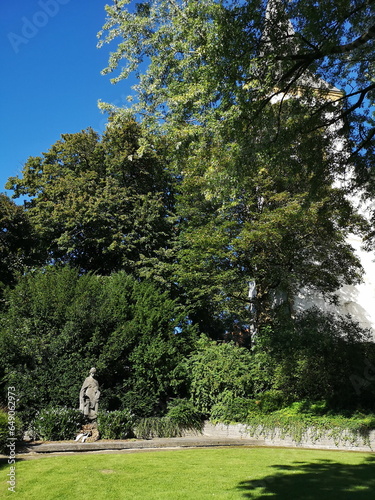 Grünanlage mit Frauenstatue bei Sonnenschein vor der Alexanderkirche in der Altstadt von Oerlinghausen bei Bielefeld am Hermannsweg im Teutoburger Wald in Ostwestfalen-Lippe