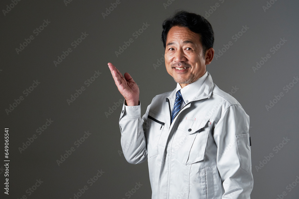 左側を手の平で指す作業員　黒背景