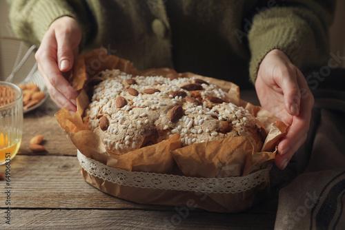 Woman with delicious Italian Easter dove cake (traditional Colomba di Pasqua) at wooden table, closeup