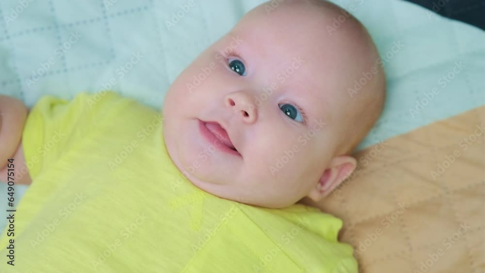 Portrait of a newborn baby in a yellow bodysuit.
