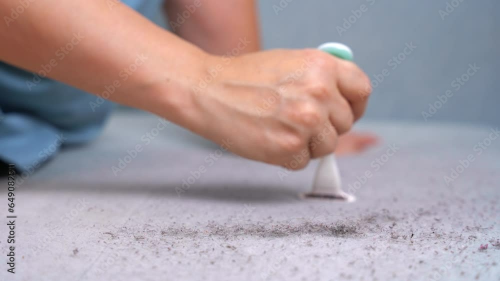 Hand holds plastic razor, cuts pellets from surface of sofa. Dry cleaning of upholstered furniture, DIY life hack worker removes dirt from fabric of couch, carefully runs a sharp blade, collects dust