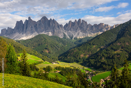 Breathtaking view of lush green Val di Funes valley with rustic cottages nestled amidst pristine alpine landscape against backdrop of rugged peaks  © JackF