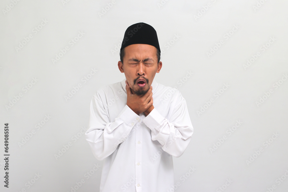 an Unwell young Indonesian man, wearing a songkok, peci, or kopiah, is coughing and sneezing, suffering from a cough, flu, and allergies, isolated on a white background an Unwell young Indonesian man, wearing a songkok, peci, or kopiah, is coughing and sneezing, suffering from a cough, flu, and allergies, isolated on a white background