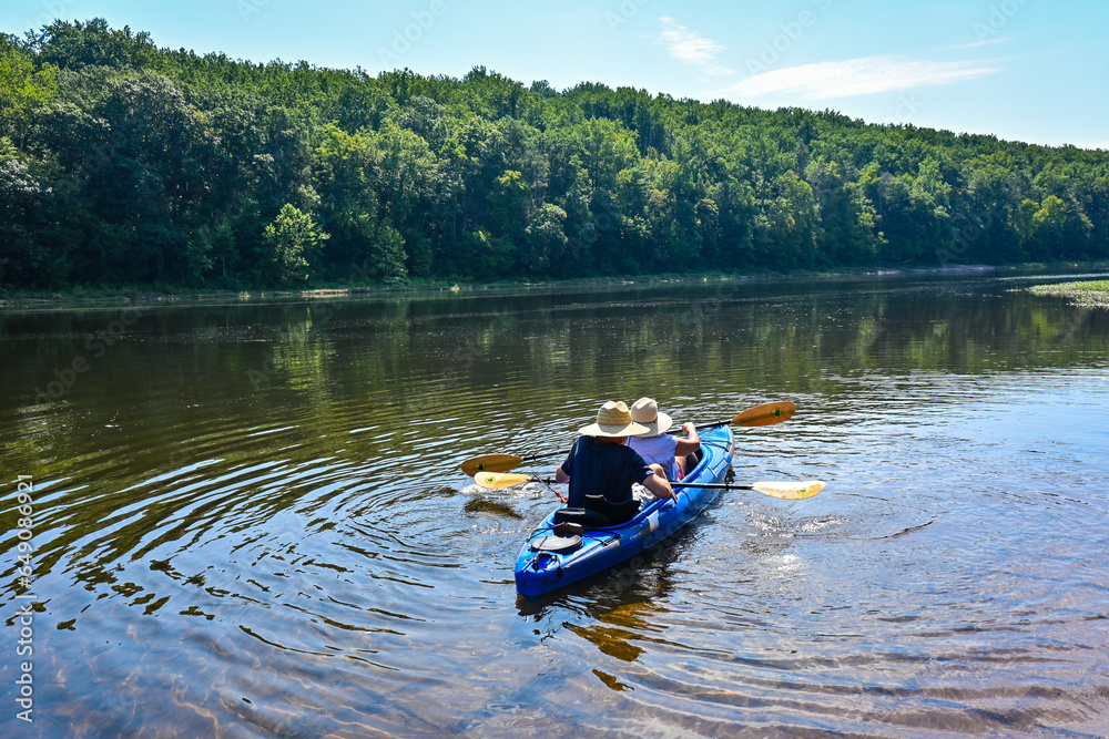 A couple kayaking in the lake with sun hats on a hot summer day A couple kayaking in the lake with sun hats on a hot summer day