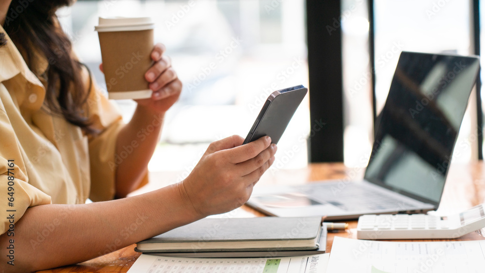 Businesswomen drink coffee and read data on smartphone while working business project at workplace Businesswomen drink coffee and read data on smartphone while working business project at workplace