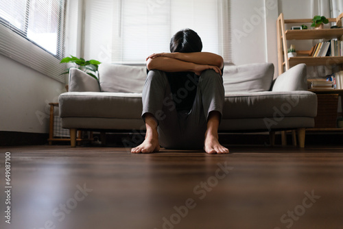 Man with mental health problem sitting on floor to resting head on his arms with depressed emotion