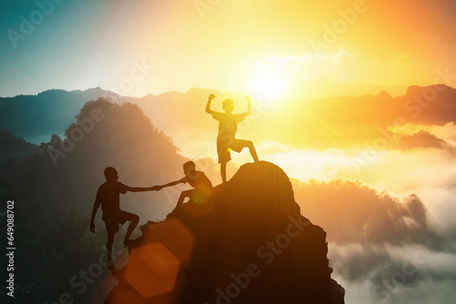 Silhouette friends helping each other and with teamwork, trying to reach top of the mountains during summer sunset, Business, success,victory,leadership,achievement concept. Freedom travel adventure. photo