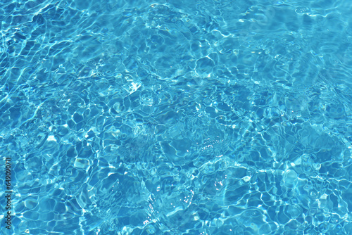 Defocus blurred transparent blue colored clear calm water surface texture with splashes reflection. Trendy abstract nature background. Water waves in sunlight with copy space. Blue watercolor shine