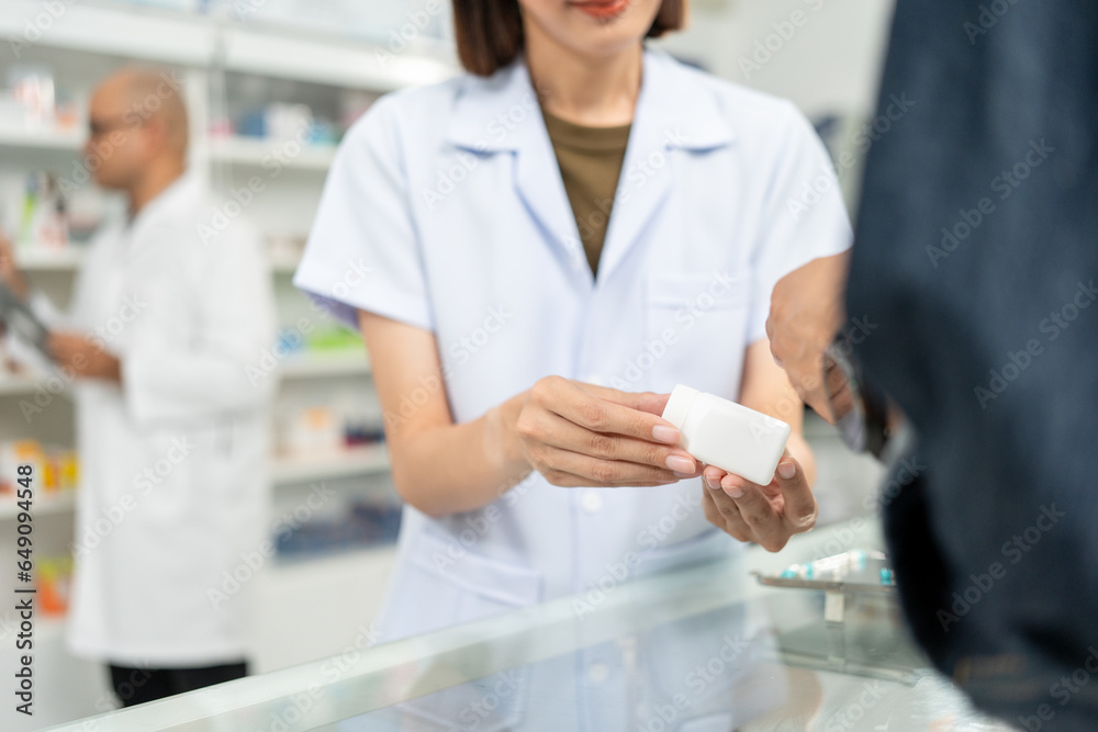 Obraz premium Pharmacist recommends medicines to customers.Taking the questions of medication. Asian female pharmacist giving prescription medications to customers at drugstore shelves.