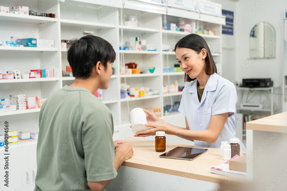 Pharmacist recommends medicines to customers.Taking the questions of medication. Asian female pharmacist giving prescription medications to customers at drugstore shelves.