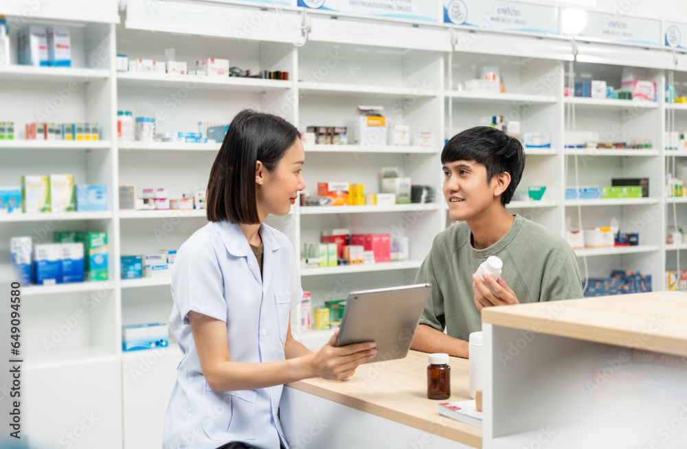 Pharmacist recommends medicines to customers.Taking the questions of medication. Asian female pharmacist giving prescription medications to customers at drugstore shelves.