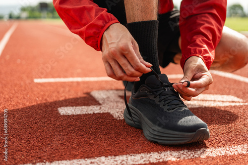 Hands man runners tie shoelaces prepared to run on track. Young athlete man wearing sportswear at running track sport stadium.Training athlete work out at outdoor concept.