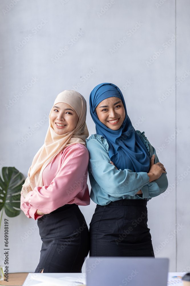 Portrait of successful and happy Two Young muslim women in hijab, office worker smiling and looking at camera with crossed arms, working inside modern office. Portrait of successful and happy Two Young muslim women in hijab, office worker smiling and looking at camera with crossed arms, working inside modern office.