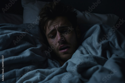 Dramatic Portrait of Young depressed man crying in bed