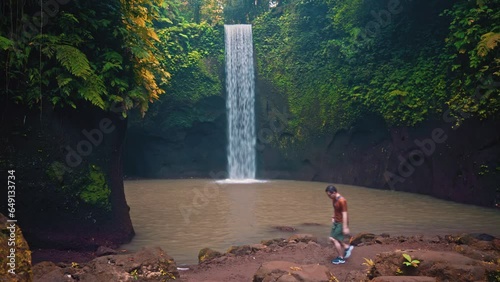 Silhouette travel people enjoy beautiful Tibumana Waterfall Bali in tropical rainforest jungle Ubud Bali, Indonesia 4K photo