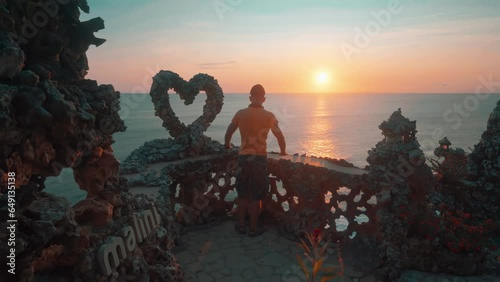 Travel people standing on top mountain cliff above the ocean near famous landmark Bali, Uluwatu temple on background sunset. Bali Indonesia 4K  photo