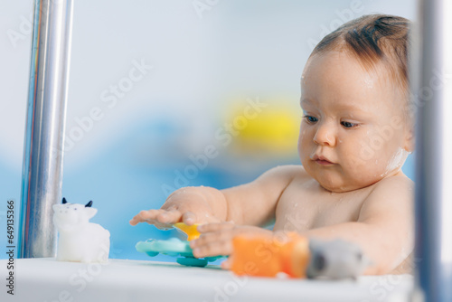 Portrait happy baby girl play with toy in swimming pool, teaching small swimmer. Concept healthcare sport for infant