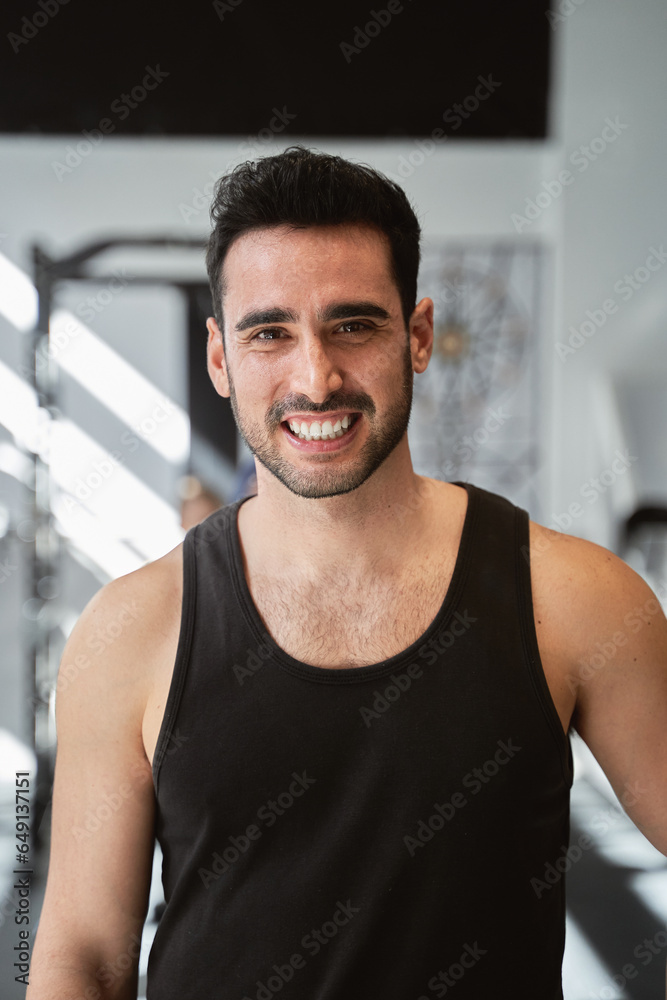 Portrait of a fitness man looking at camera and smiling while posing in the gym. Sports concept. Portrait of a fitness man looking at camera and smiling while posing in the gym. Sports concept.