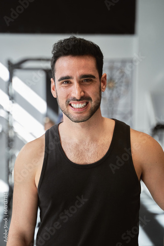 Portrait of a fitness man looking at camera and smiling while posing in the gym. Sports concept.