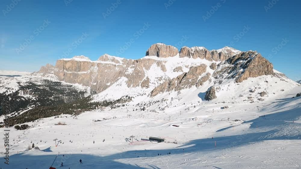 View of a ski resort piste with people skiing in Dolomites in Italy. Ski area Belvedere. Canazei, Italy. Horizontal camera pan View of a ski resort piste with people skiing in Dolomites in Italy. Ski area Belvedere. Canazei, Italy. Horizontal camera pan