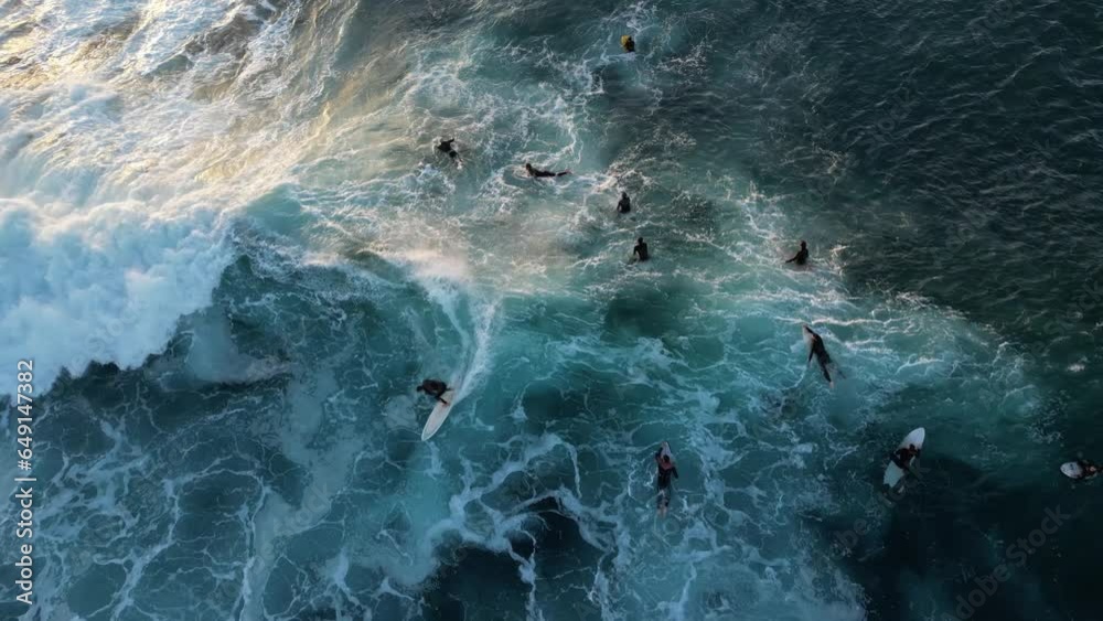 Aerial top down shot of surfer surfing on wave between group surfer in Indian Ocean during sunset time with sun rays. slow motion