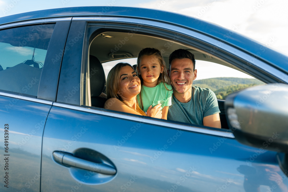 The family is sitting in the car, they are ready for a family trip before going to school at the end of the summer