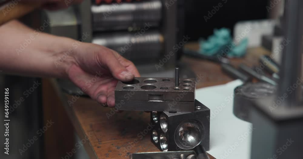 jeweler presses out a silver blank using molds and a hammer in preparation for the production of jewelry or a ring jeweler presses out a silver blank using molds and a hammer in preparation for the production of jewelry or a ring