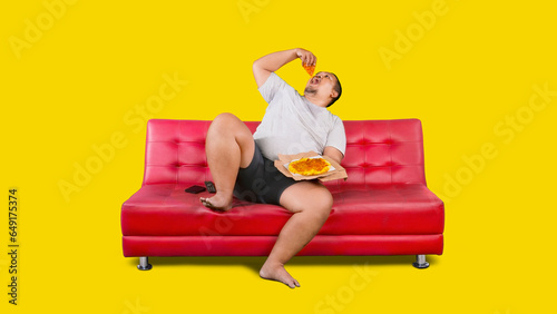 Overweight Asian guy eating a box of pizza while sitting on a couch