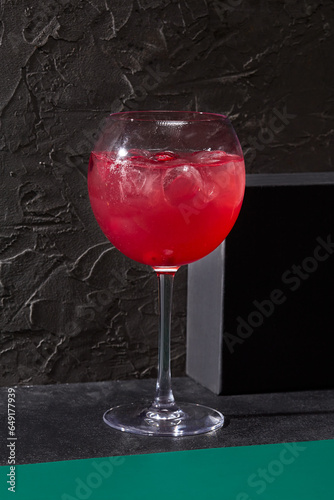 Berry lemonade elegantly presented in a wine glass against a stark black background. Minimalist design, ideal for a bar card