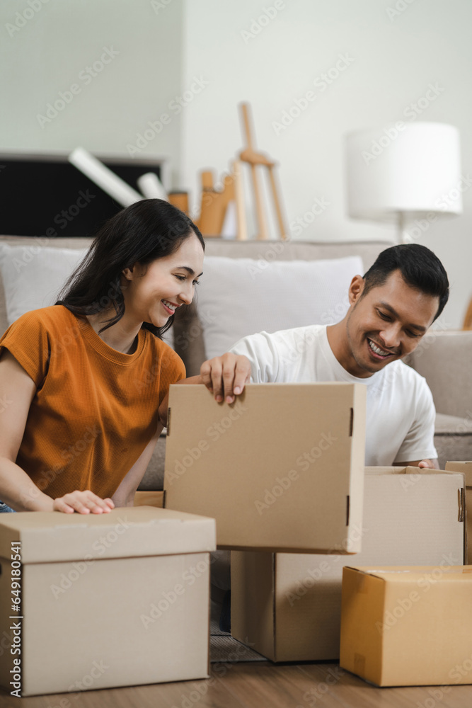 young couple helps put things in boxes and prepares, smiling happy moving to a new house. young couple helps put things in boxes and prepares, smiling happy moving to a new house.