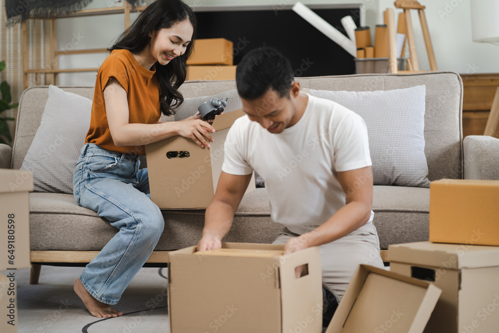 young couple helps put things in boxes and prepares, smiling happy moving to a new house. young couple helps put things in boxes and prepares, smiling happy moving to a new house.