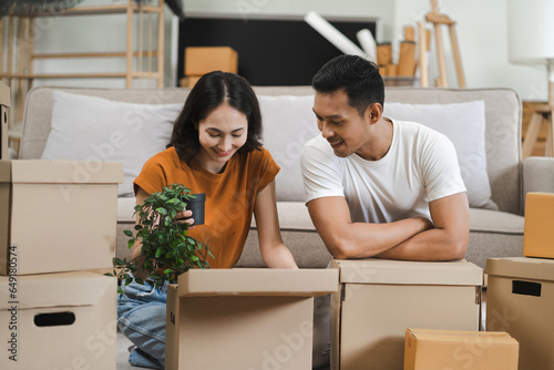 young couple helps put things in boxes and prepares, smiling happy moving to a new house. © NINENII