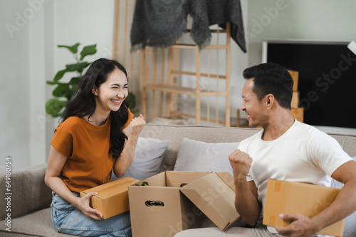 Successful young couple is moving to a nice new place, around boxes with their belongings. The room is very bright and bright, they are wearing casual clothes. © NINENII