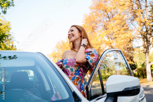 Happy woman standing by car on street photo