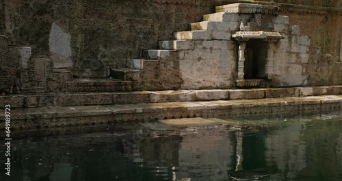 Water storage inside Toorji Ka Jhalra Baoli stepwell, one of water sources in Jodhpur, Rajasthan, India. Sunny day, water ripples reflect walls of the pool. Camera horizontal pan photo