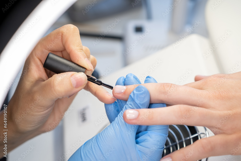 Nail care procedure in a beauty salon. Female hands and tools for manicure, process of performing manicure in beauty salon. Concept spa body care. Gloved hands of a skilled manicurist cutting cuticles Nail care procedure in a beauty salon. Female hands and tools for manicure, process of performing manicure in beauty salon. Concept spa body care. Gloved hands of a skilled manicurist cutting cuticles