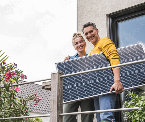 Couple standing on balcony with unmounted solar panel
