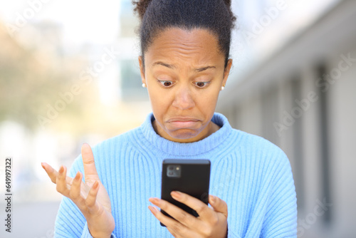 Perplexed black woman checking cell phone