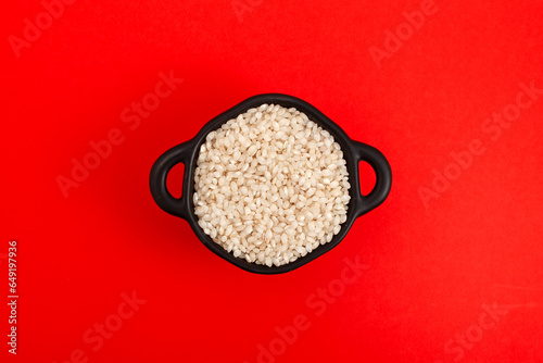 Photos Uncooked Calasparra rice or or arroz calasparra in pan on red background, top view