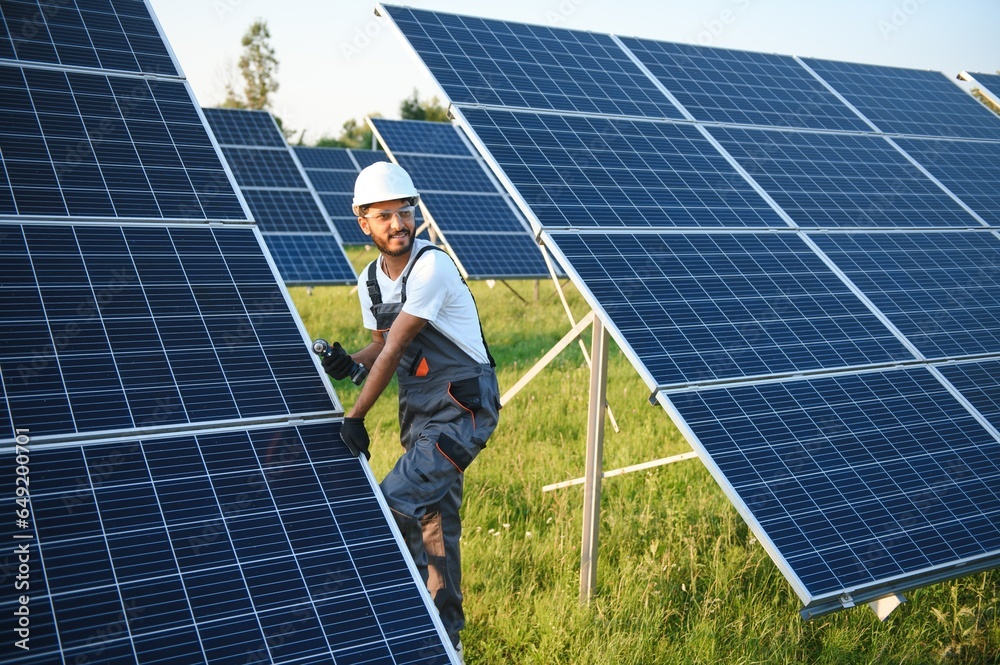 An Indian male worker is working on installing solar panels in a field An Indian male worker is working on installing solar panels in a field