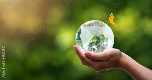 a globe crystal on hands in blurred nature background, world earth day, save environment and planet, clean ecology , energy saving concept. .