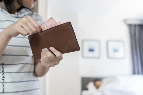 Teenager girl trying to steal money carefully pulling cash out of wallet skillfully,moving quietly in her parent's bedroom at home,bad habit,behavior of stealing for hangout,shopping,lifestyle concept