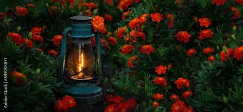 old kerosene lamp in flower garden, dark abstract natural background. Mystery magic atmosphere. fairy evening, vintage lantern and red-orange marigold flowers. symbol of end summer, autumn season photo