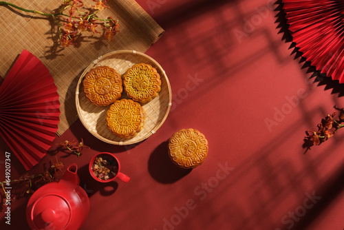 Photography Chinese Mid-Autumn Festival concept made from mooncakes, set of tea and beautiful flower branches on red background