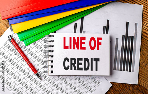 LINE OF CREDIT text on notebook with pen, folder on a chart background