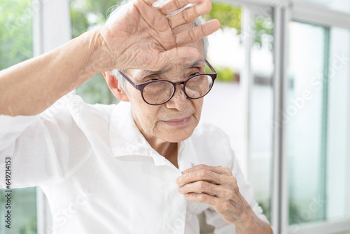 Tired asian elderly woman have headaches,check her body temperature,touching forehead with her hand,feel hot,dizzy,concerned about Summer Flu in the hot weather,Heat stroke attack,health care concept