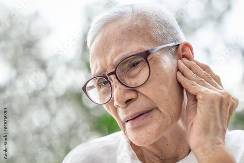 Old elderly woman experiencing ear pain,Swimmer's Ear,Perforated eardrums caused by trauma or infection,painful and discomfort in the ear canal,illness,health problems,lifestyle,health care concept photo